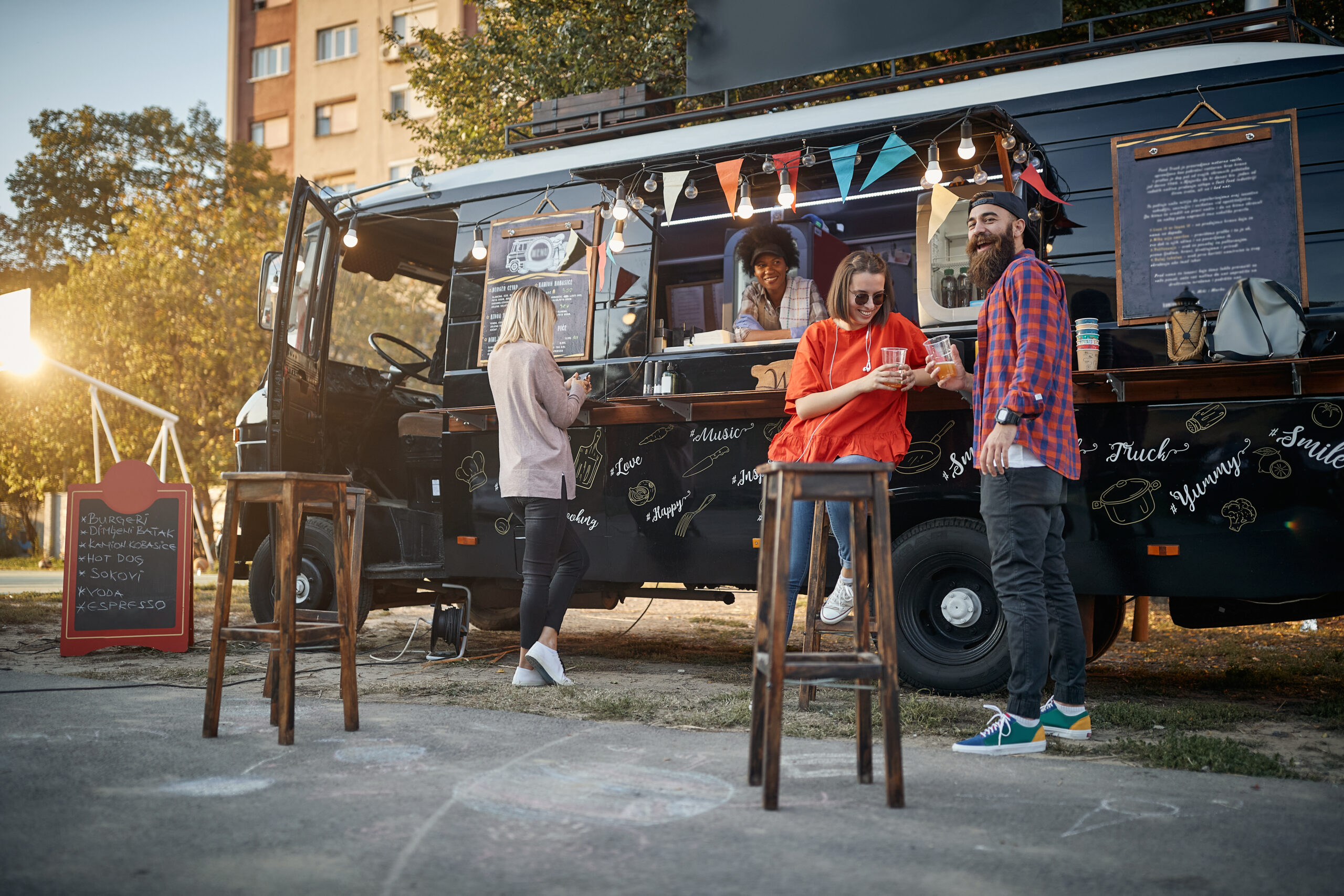 hipster with friends in front of modified truck for mobile fast food service looking at camera
